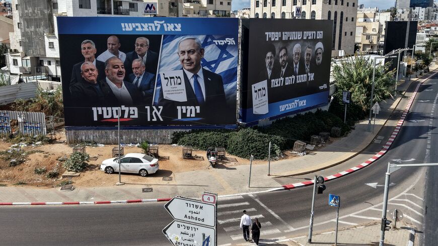 Pedestrians cross a street in front of a banner featuring Israeli Prime Minister Benjamin Netanyahu