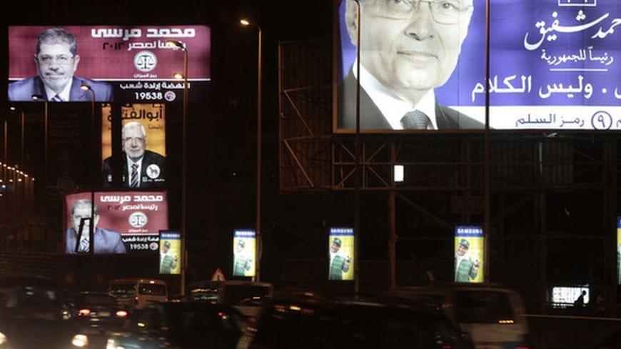 Vehicles drive under election campaign billboards of presidential candidate and former prime minister Ahmed Shafiq (R), the head of the Muslim Brotherhood's political party and the Brotherhood's presidential candidate Mohamed Mursi (L), and presidential candidate and former leader of the Muslim Brotherhood Abdel Moneim Abu El Fotouh during the last campaign rally night in Cairo May 20, 2012. The election that starts on Wednesday is the last stage in a messy transition to democracy, overseen by generals who 