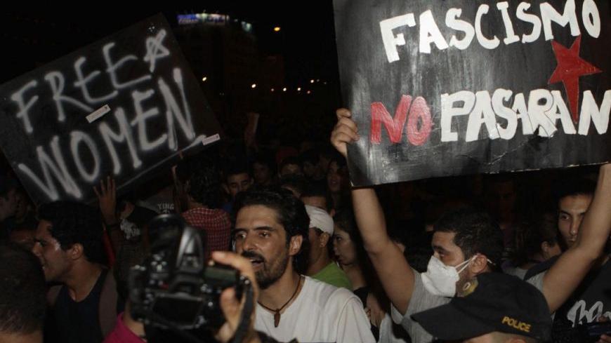 Protesters hold signs as they stand in front of riot police during a demonstration in Tunis August 13, 2012. Thousands of Tunisians rallied on Monday to protest against what they see as a push by the Islamist-led government for constitutional changes that would degrade women's status in one of the Arab world's most liberal nations. REUTERS/Zoubeir Souissi (TUNISIA - Tags: POLITICS CIVIL UNREST CRIME LAW)