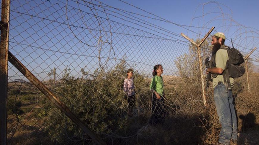A Jewish settler participating in a drill held by the settler's security response teams, speaks to girls through a fence in the West Bank settlement of Kiryat Arba September 14, 2011. The drill simulated violence that could erupt ahead of the upcoming Palestinian bid for statehood at the United Nations. REUTERS/Ronen Zvulun (WEST BANK - Tags: POLITICS CIVIL UNREST)