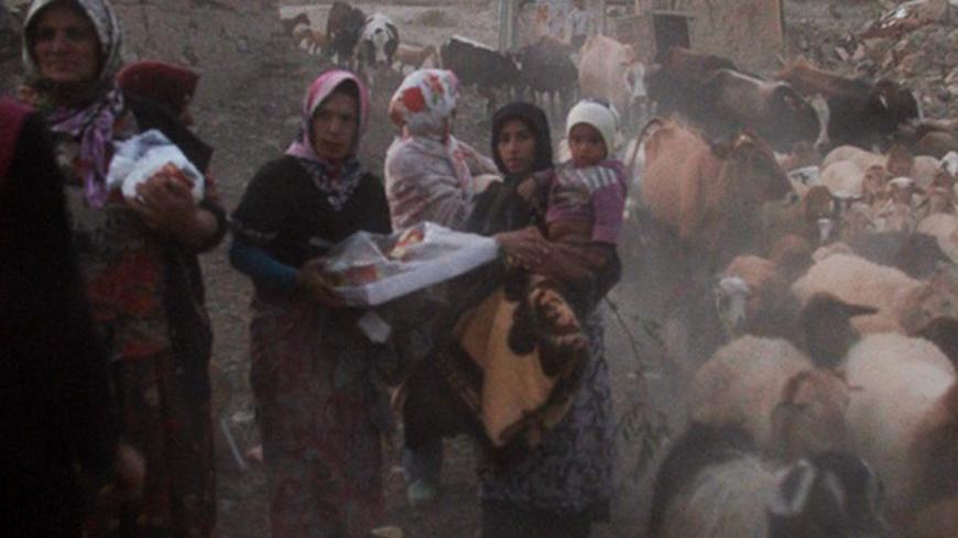 An earthquake victim carries clothing and other items in the earthquake-stricken town of Azerbaijan in Iran, August 13, 2012. Rescue workers in Iran on Tuesday recovered more bodies three days after two powerful earthquakes struck the northwest of the country, killing more than 300 people, but officials played down reports that casualty numbers may still sharply rise. Picture taken August 13, 2012. REUTERS/Farshid Tighehsaz/ISNA (IRAN - Tags: DISASTER) FOR EDITORIAL USE ONLY. NOT FOR SALE FOR MARKETING OR A