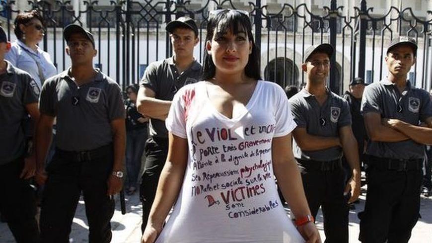 A protester poses in front of police officers during a demonstration against charges of indecency filed against a woman raped by two police officers, in front of the court in Tunis October 2, 2012. Amnesty International has called for the indecency charges against the woman, who prefers to remain anonymous, filed by the same two police officers found guilty and jailed for raping her, to be dropped. REUTERS/Zoubeir Souissi (TUNISIA - Tags: POLITICS CIVIL UNREST CRIME LAW)
