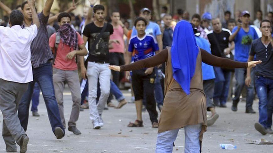 A woman stands in front of protesters during clashes between supporters and opponents of the Muslim Brotherhood and President Mohamed Mursi in Tahrir square in Cairo October 12, 2012. Opponents and supporters of Mursi clashed in Cairo on Friday in the first street violence between rival factions since the Islamist leader took office.
  REUTERS/Mohamed Abd El Ghany (EGYPT - Tags: POLITICS CIVIL UNREST)