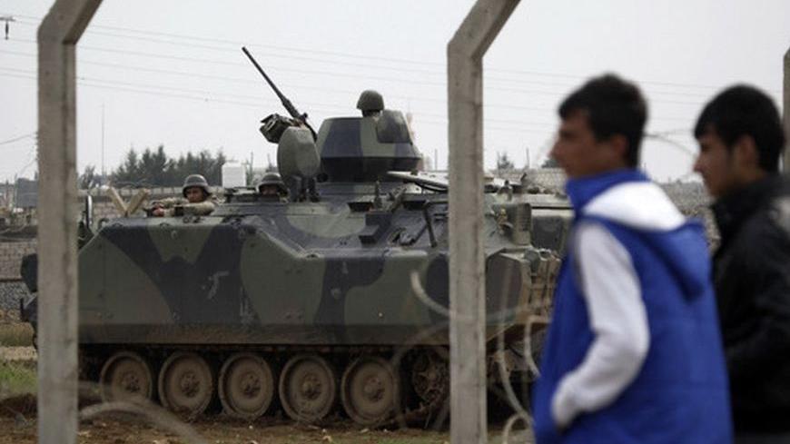 A Syrian youth from the northern Syrian town of Ras al-Ain reacts in front of the border fence near Turkish soldiers in a military vehicle at the Turkish border town of Ceylanpinar, November 25, 2012. Iran said Turkey's plans to deploy Patriot defensive missiles near its border with Syria would add to the region's problems, as fears grow of the Syrian civil war spilling across frontiers. REUTERS/Amr Abdallah Dalsh  (TURKEY - Tags: POLITICS CONFLICT)