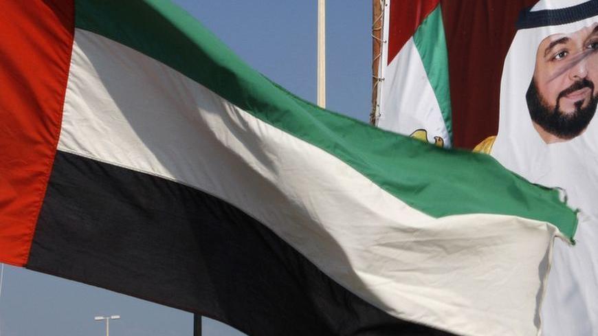 A United Arab Emirates flag waves in front of a big poster of President Sheikh Khalifa bin Zayed al-Nahayan in Abu Dhabi December 15,2009. Abu Dhabi threw its flashy but debt-laden neighbour Dubai a $10 billion lifeline to head off a bond default, cheering Gulf and global markets on Monday but raising questions about the undisclosed terms.REUTERS/Ahmed Jadallah (UNITED ARAB EMIRATES - Tags: TRAVEL SOCIETY BUSINESS CITYSCAPE)