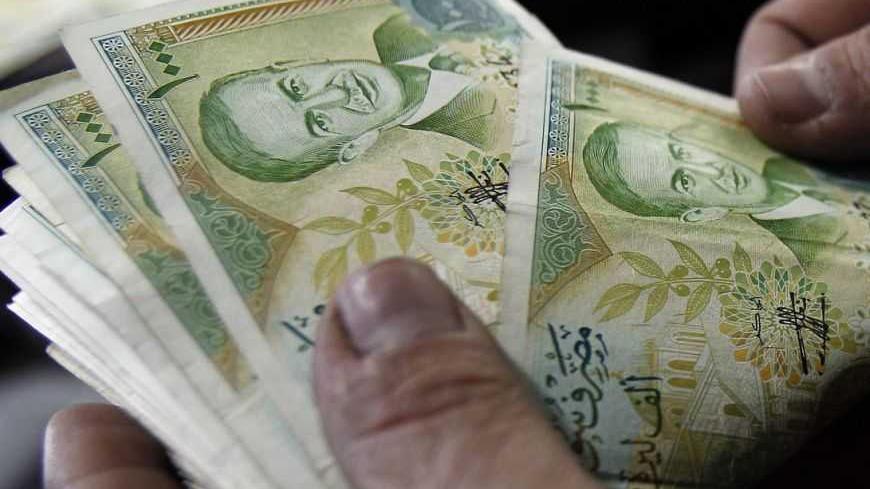 A cashier counts Syrian currency notes in Amman December 6, 2011. Jordanian money changers said on Tuesday demand on the Syrian pound has plummeted since unprecedented Arab economic sanctions against Damascus, and its exchange rate against the dollar has slipped on the black market by at least 7 percent to nearly 57 pounds.  REUTERS/Ali Jarekji  (JORDAN - Tags: BUSINESS POLITICS)