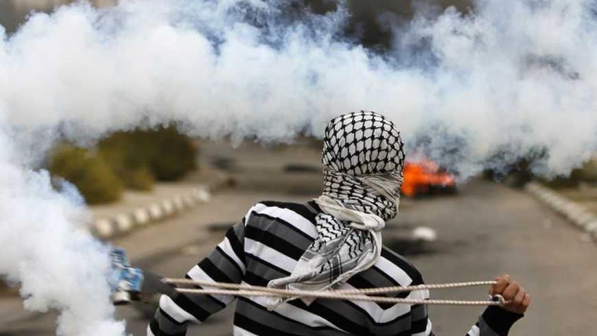 A Palestinian stone-thrower uses a sling to throw back a tear gas canister fired by Israeli security forces during clashes outside Ofer prison near the West Bank city of Ramallah November 18, 2012. The clashes broke out following a protest against Israel's military operation in the Gaza Strip. REUTERS/Mohamad Torokman (WEST BANK - Tags: POLITICS CIVIL UNREST TPX IMAGES OF THE DAY) - RTR3AKLT