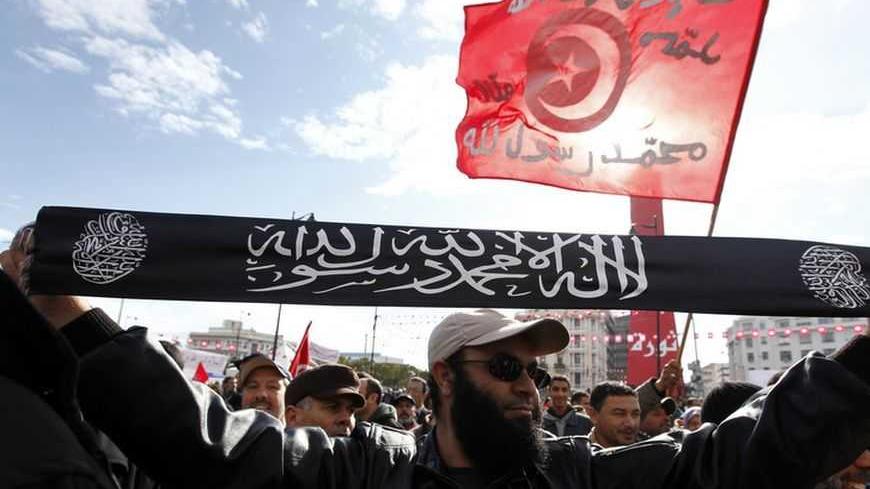 A man from the Salafist faction holds up a banner that reads "There is no god but God, and Muhammad is the messenger of God", on the second anniversary of the Tunisian Revolution at Avenue Habib Bourguiba in Tunis January 14, 2013. Thousands of Tunisians protested against the Islamist-led government on Monday, exactly two years after the overthrow of President Zine El Abidine Ben Ali in a popular revolt that inspired others across the Arab world. In the same street, about 2,000 supporters of the Islamic-led
