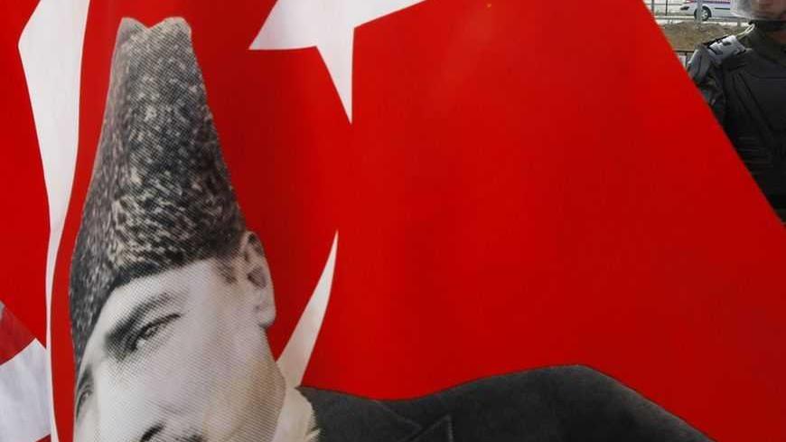 A gendarme soldier stands in front of protesters as a Turkish flag with a portrait of Mustafa Kemal Ataturk, founder of modern Turkey, flutters outside Silivri prison, some 70 km (43.5 miles) west of Istanbul, during the trial of a shadowy-right wing group taking place in the heavily-guarded prison, October 23, 2008. The trial of Ergenekon, a shadowy right-wing group, resumed in Turkey on Thursday on charges of trying to topple Prime Minister Tayyip Erdogan's government.  REUTERS/Fatih Saribas  (TURKEY) - R