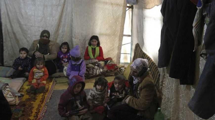 A Syrian refugee woman carries her child as they sit inside a tent near Tripoli January 9,2013. More than 600,000 Syrian refugees have fled to neighbouring countries exposed to the storm. Many in Lebanon and Jordan were forced to move after their tents were flooded. REUTERS/Omar Ibrahim (LEBANON - Tags: ENVIRONMENT DISASTER CIVIL UNREST)