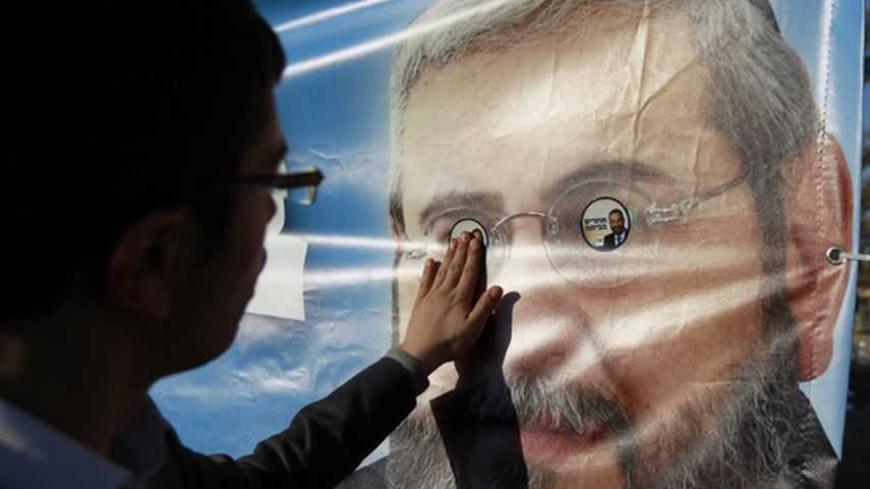 An ultra-Orthodox Jew places a sticker that depicts Shas party leader Aryeh Deri onto a campaign banner depicting Am Shalem party leader Haim Amsalem during an annual pilgrimage to the gravesite of Rabbi Yisrael Abuhatzeira, a Moroccan-born sage and kabbalist also known as the Baba Sali, in the southern town of Netivot January 14, 2013. A fixture in successive governments, the ultra-Orthodox Shas party draws its support from the fast-growing community of religious Jews of Middle Eastern origin whose spiritu