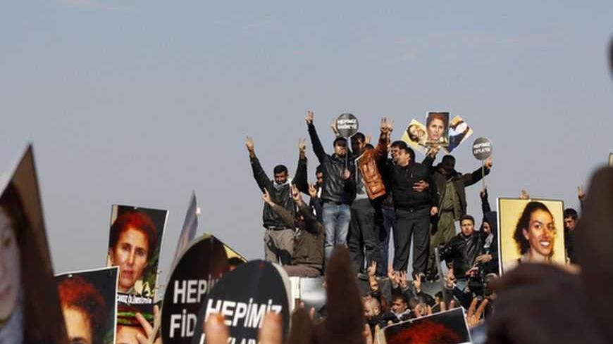 People hold signs as they attend the funeral ceremony of the three Kurdish activists shot in Paris, in Diyarbakir, the largest city in Turkey's mainly Kurdish southeast, January 17, 2013. The bodies of the activists, including that of Kurdistan Workers Party (PKK) co-founder Sakine Cansiz, arrived by plane on Wednesday evening in Diyarbakir. REUTERS/Umit Bektas (TURKEY - Tags: POLITICS OBITUARY CIVIL UNREST)