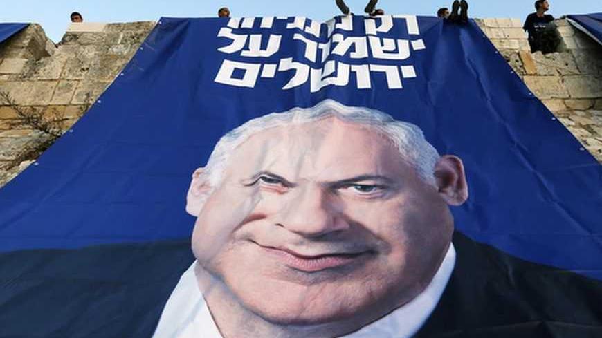 Likud-Yisrael Beitenu activists sit atop a wall surrounding Jerusalem's Old City after they hung a campaign banner depicting Israel's Prime Minister Benjamin Netanyahu January 20, 2013. Netanyahu said on Saturday a country with as many enemies as Israel cannot afford a weak ruling party, after polls ahead of Tuesday's parliamentary election showed a slide in his support. The banner reads "Only Netanyahu will protect Jerusalem". REUTERS/Ronen Zvulun (JERUSALEM - Tags: POLITICS ELECTIONS TPX IMAGES OF THE DAY