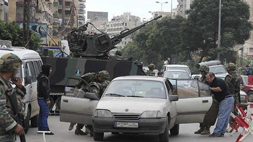 Lebanese army soldiers inspect a car at a checkpoint in the port city of Tripoli, northern Lebanon, during clashes between Sunni Muslims and Alawites December 6, 2012. Two men were killed by sniper fire in Tripoli on Thursday during sectarian clashes between gunmen loyal to opposing sides in neighbouring Syria's civil war, residents said. REUTERS/Stringer    (LEBANON - Tags: POLITICS CIVIL UNREST MILITARY TRANSPORT)