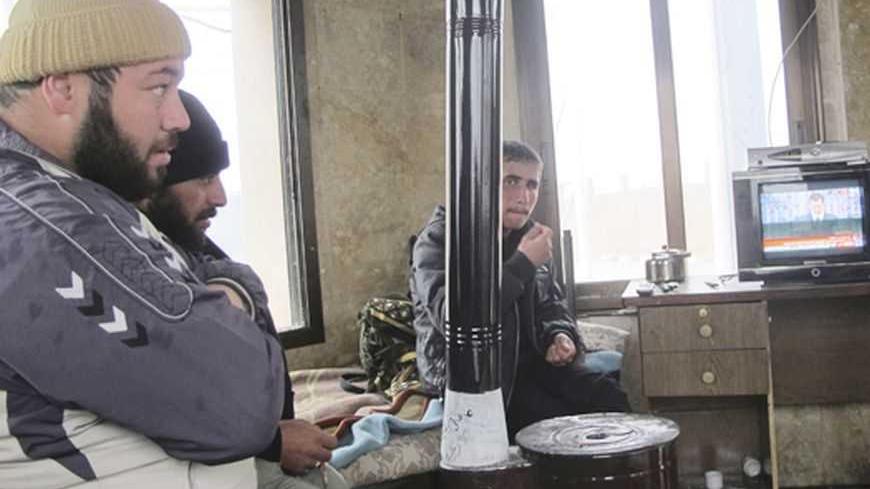 Men watch a television broadcast of Syria's President Bashar al-Assad speaking from the capital's Opera House, inside a room in the city of Azaz in north Aleppo January 6, 2013. REUTERS/Abdalghne Karoof (SYRIA - Tags: CONFLICT)