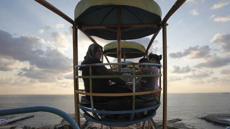 A Muslim family enjoy a ride on a ferris wheel at an amusement park during Eid al-Fitr in Beirut August 30, 2011. Muslims around the world celebrate Eid al-Fitr to mark the end of Ramadan, the holiest month in the Islamic calendar.   REUTERS/Cynthia Karam    (LEBANON - Tags: RELIGION) - RTR2QK5N