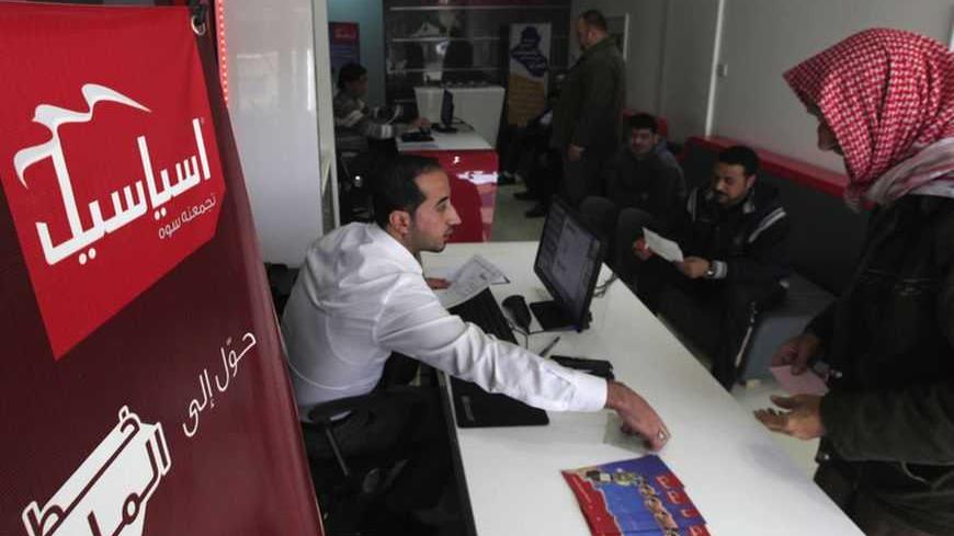 An Iraqi employee sells Asiacell simcards for cell phones in the Asiacell company headquarters in Baghdad, December 30, 2012. Investors will get a chance to buy into the country's oil-fuelled economic boom this month as Asiacell seeks to raise at least $1.35 billion by floating 25 percent of its share capital on the Baghdad stock market. Picture taken December 30, 2012. To match story IRAQ-TELECOMS/ REUTERS/Saad Shalash (IRAQ - Tags: BUSINESS TELECOMS) - RTR3C1RM