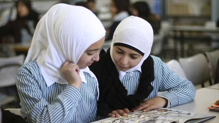 Palestinian students share a schoolbook while studying in the school library in the West Bank city of Ramallah February 4, 2013. Israelis and Palestinians depict each other in schoolbooks as an enemy and largely deny their adversary's history and existence, according to a U.S. government-funded study published on Monday. REUTERS/Mohamad Torokman (WEST BANK - Tags: POLITICS EDUCATION) - RTR3DCH6