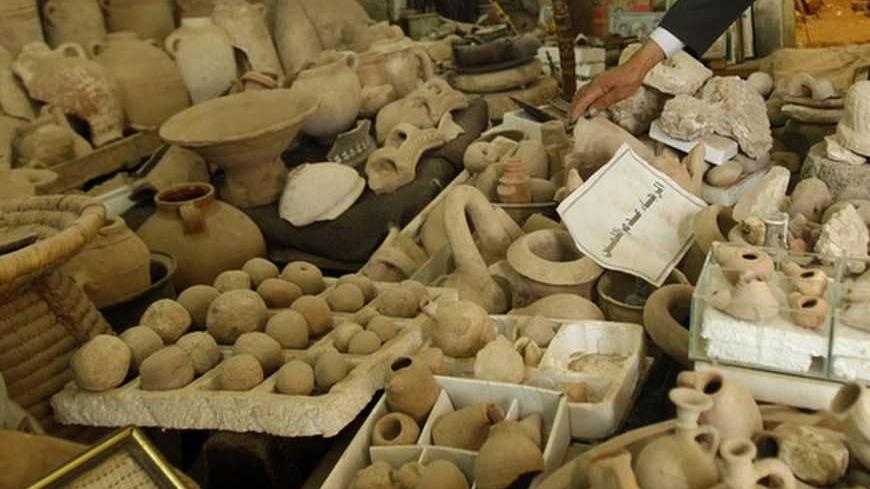Palestinian amateur archaeologist Waleed Al-Aqqad touches a clay jar from his collection of ancient artefacts at his house, which he was turned into a museum, in Khan Younis in the southern Gaza Strip April 3, 2011. Five thousand years of fascinating history lie beneath the sands of the Gaza Strip, from blinded biblical hero Samson to British general Allenby. Picture taken April 3, 2011. To match Feature PALESTINIANS-ARCHAEOLOGY      REUTERS/Ibraheem Abu Mustafa (GAZA  - Tags: ENTERTAINMENT)   - RTR2LFVK
