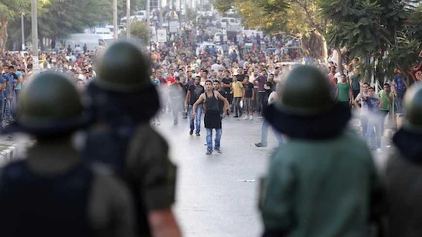 Palestinians security officers stand in front of protesters during clashes at a demonstration against high living costs and the government in the West Bank city of Hebron September 10, 2012. Palestinian youths attacked a local police station and other government buildings in Hebron on Monday as protests against the rising cost of living in the occupied West Bank turned increasingly violent. REUTERS/Darren Whiteside (WEST BANK - Tags: POLITICS CIVIL UNREST) - RTR37S7M