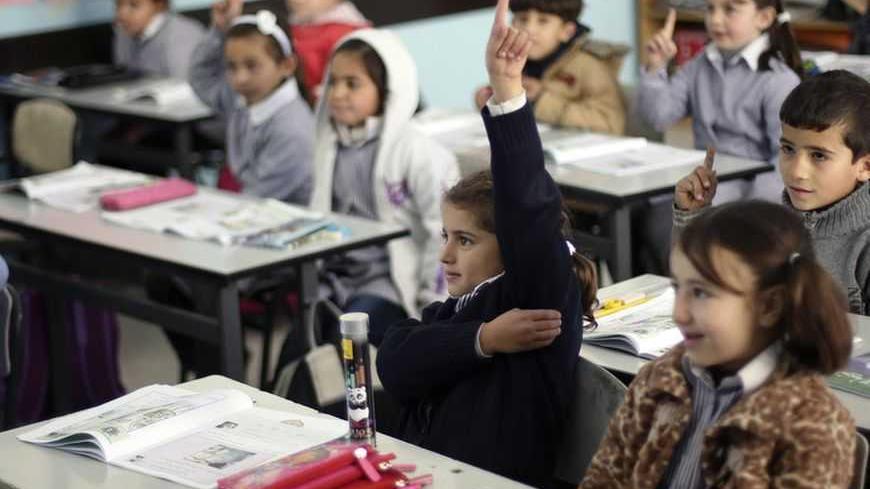Palestinian first-graders sit with their schoolbooks during class in the West Bank city of Ramallah February 4, 2013. Israelis and Palestinians depict each other in schoolbooks as an enemy and largely deny their adversary's history and existence, according to a U.S. government-funded study published on Monday. REUTERS/Mohamad Torokman (WEST BANK - Tags: EDUCATION POLITICS) - RTR3DCHK