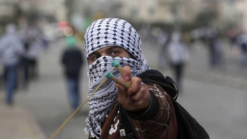 A Palestinian uses a slingshot to hurl a stone towards Israeli troops during clashes outside Israel's Ofer military prison near the West Bank city of Ramallah February 28, 2013. The death of a Palestinian prisoner in disputed circumstances in an Israeli jail on Saturday, together with a hunger strike by four other Palestinian inmates, have touched off violent protests over the past several weeks outside the prison and in West Bank towns. REUTERS/Mohamad Torokman (WEST BANK - Tags: POLITICS CIVIL UNREST) - R