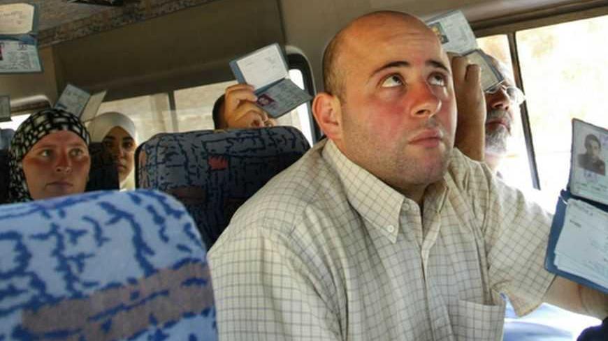 Palestinians show their ID cards to Israeli police inside a bus in Jerusalem August 12, 2004. Investigators were still examining if members of a militant cell which bombed a West Bank checkpoint Wednesday were still at large. The blast killed two Palestinians and wounded 16 people. REUTERS/Gil Cohen Magen  GCM/SM - RTR8GY0