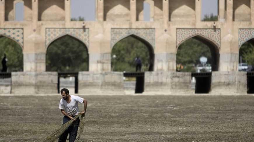 A fisherman tries to catch fish at the dried-up Zayanderood River, with the Khajoo Bridge seen in the background, in Isfahan, 450 km (281 miles) south of Tehran, June 27, 2008. The river dried up due to low rainfall and the water being re-channelled for hydroelectricity purposes. REUTERS/Morteza Nikoubazl (IRAN) - RTX7EU6