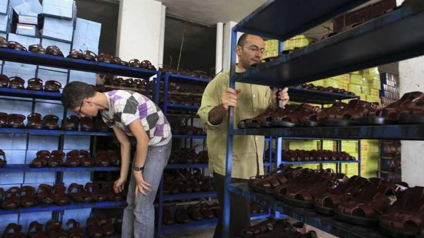 Workers place newly made leather sandals in the storage area of a shoe factory in Hebron June 29, 2010. Cattle owners in Hebron, the West Bank city known for its leather and carpentry industries, have turned to selling hides from cattle slaughtered for meat to shoe manufacturers. The hides are processed at special facilities in the West Bank and the leather is sold to local shoe factories. Picture taken June 29, 2010.  REUTERS/Ammar Awad (WEST BANK - Tags: BUSINESS) - RTR2FY27