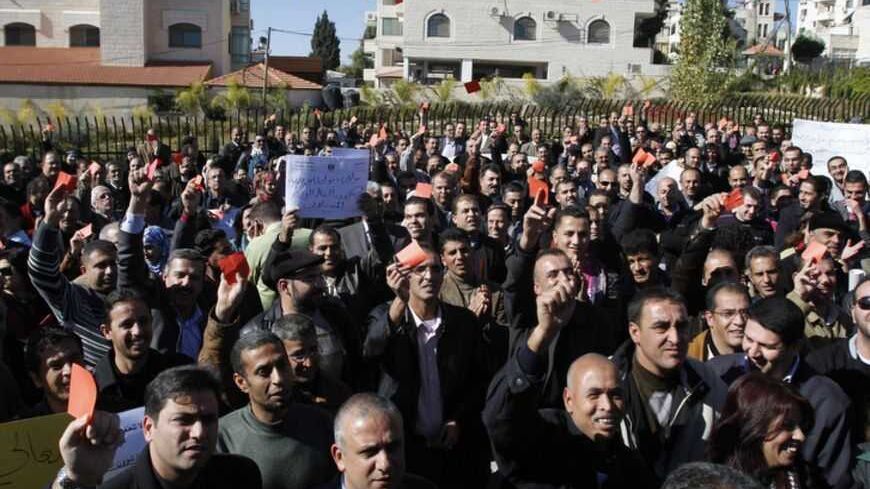 Palestinian government employees hold pieces of red paper during a protest against the Labour Minister Ahmad Majdalani in front of Prime Minister Salam Fayyad's office in West Bank city of Ramallah November 29, 2011. Palestinian Economy Minister Hassan Abu Libdeh has been charged with financial wrongdoing, court sources said on Tuesday, piling pressure on Fayyad's beleaguered government. Majdalani, also faced pressure to resign on Tuesday because of unguarded comments broadcast on local radio, when he brand