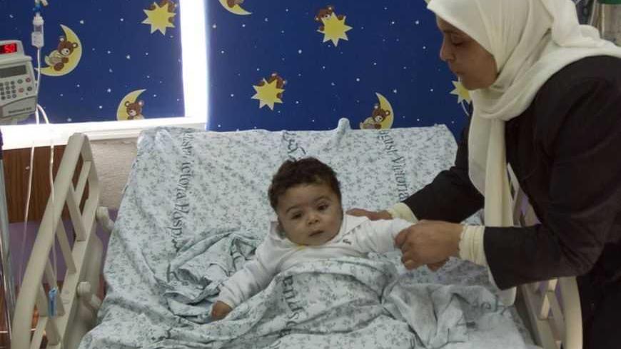 A Palestinian woman lifts her son, who is being treated for cancer, in the paediatric ward of Augusta Victoria Hospital in East Jerusalem November 6, 2012. Six hospitals in East Jerusalem face a financial crisis because the aid-dependent Palestinian Authority has been unable to meet payments for their services, jeopardizing the healthcare of thousands of West Bank patients. REUTERS/Baz Ratner (JERUSALEM - Tags: HEALTH POLITICS BUSINESS) - RTR3A2BM