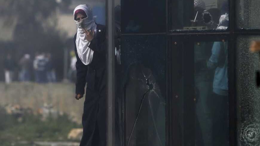 A Palestinian protester holds stones as she stands near broken glass during clashes with Israeli soldiers outside Israel's Ofer military prison near the West Bank city of Ramallah February 25, 2013. The death of Palestinian Arafat Jaradat on Saturday in an Israeli jail and a hunger strike by four other Palestinian inmates have raised tension in the occupied territory after repeated clashes between stone-throwers and Israeli soldiers in recent days. REUTERS/Mohamad Torokman (WEST BANK - Tags: POLITICS CIVIL 