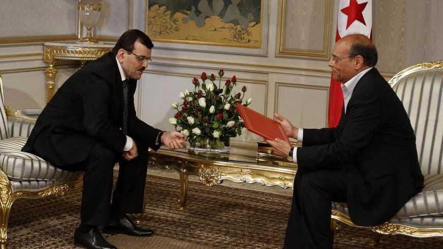 Tunisia's Prime Minister Ali Larayedh (L) gives the list of the new coalition government to President Moncef Marzouki in Tunis March 8, 2013. Larayedh unveiled a new Islamist-led coalition government on Friday that he said would serve only until an election is held before the end of the year. REUTERS/Zoubeir Souissi (TUNISIA - Tags: POLITICS) - RTR3EQOD