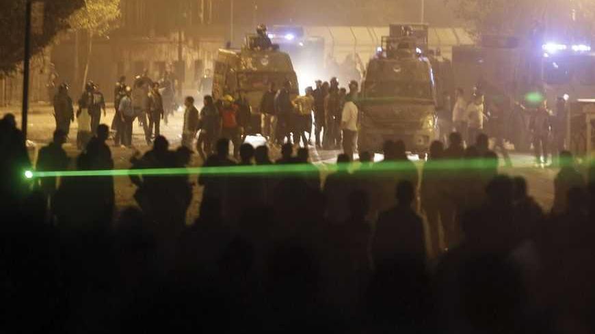 A person in the crowd uses a laser pointer as protesters, who oppose Egyptian President Mohamed Mursi, face off against riot police during clashes along Qasr Al Nil bridge, which leads to Tahrir Square in Cairo March 9, 2013. Egyptian protesters torched buildings in Cairo and tried unsuccessfully to disrupt international shipping on the Suez Canal, as a court ruling on a deadly football riot stoked rage in a country beset by worsening security. REUTERS/Amr Abdallah Dalsh (EGYPT - Tags: POLITICS CIVIL UNREST