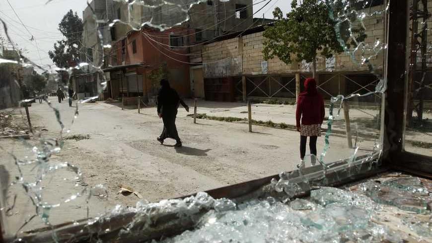 Women are seen through a broken window after clashes at Ain al-Hilweh Palestinian refugee camp near the port city of Sidon in south Lebanon March 12, 2013. Ten people were wounded and one killed during clashes between the Fatah movement and radical Islamists that started on Monday.  REUTERS/Ali Hashisho (LEBANON - Tags: POLITICS CIVIL UNREST) - RTR3EW46