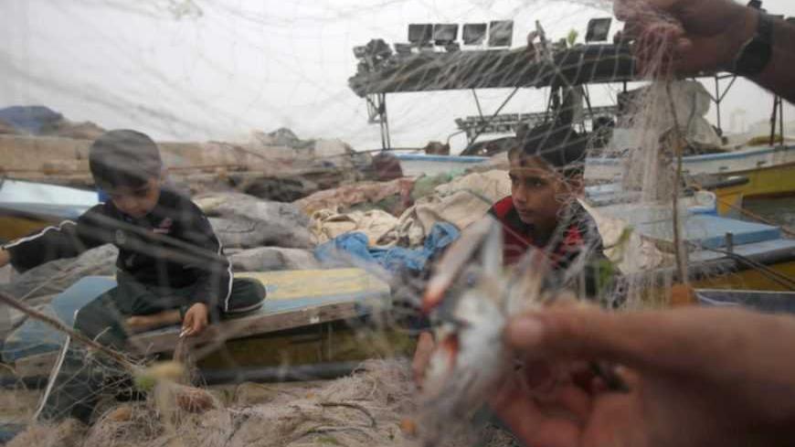 A Palestinian fisherman prepares his net with his sons at the seaport of Gaza City  March 22, 2013. Hamas complained to Egypt on Friday after Israel suspended part of a Cairo-brokered truce agreement by halving Palestinian access to fishing waters in response to a rocket attack from the Gaza Strip.  REUTERS/Ibraheem Abu Mustafa (GAZA - Tags: POLITICS CIVIL UNREST) - RTR3FBX0