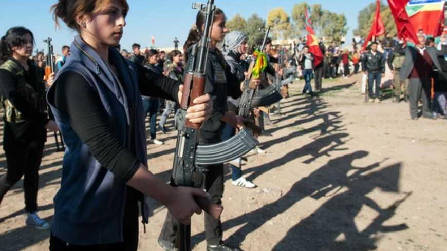 Syrian-Kurdish women and members of the Popular Protection Units (YPG), an armed opposition group fighting against the Syrian government, stand guard during the funeral of a comrade, Basil Zeydan, in the northern Syrian border village of al Qamishli on December 1, 2012. The Syrian army shelled the outskirts of Damascus in a drive to establish a secure perimeter around the capital, including the key airport road that has come under sustained rebel attack. AFP PHOTO/GIULIO PETROCCO        (Photo credit should