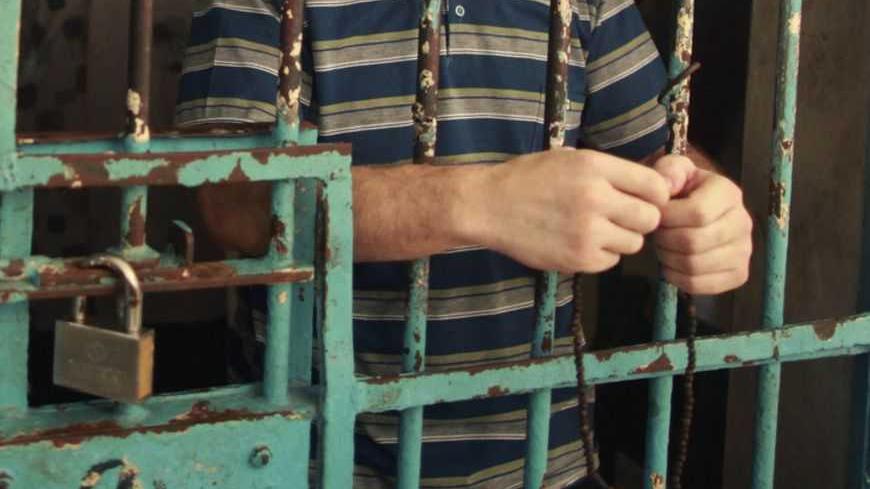 A Palestinian inmate stands behind the bars of a Hamas-run jail in Gaza City after prayers during the holy month of Ramadan July 23, 2012. REUTERS/Mohammed Salem (GAZA - Tags: POLITICS RELIGION CRIME LAW) - RTR35878
