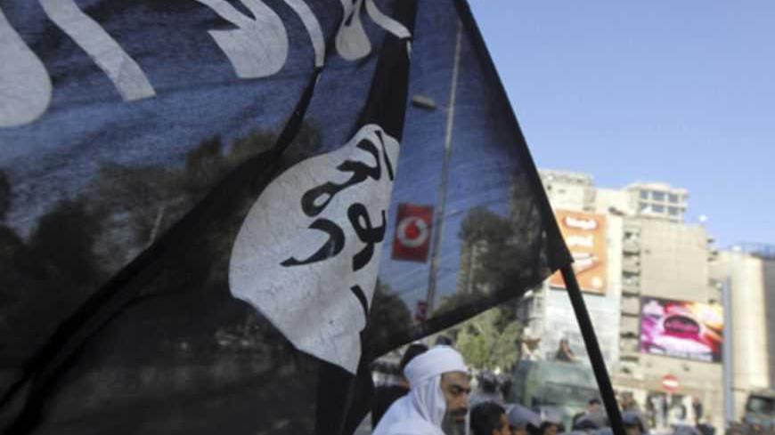 An Islamist protester holds a Salafist flag with Arabic words that read "There is no God but Allah and Mohammad is his prophet" as Egyptian security forces stand guard during a protest against the French operation in Mali outside the French embassy in Cairo January 18, 2013. REUTERS/Amr Abdallah Dalsh  (EGYPT - Tags: POLITICS CIVIL UNREST) - RTR3CLWR