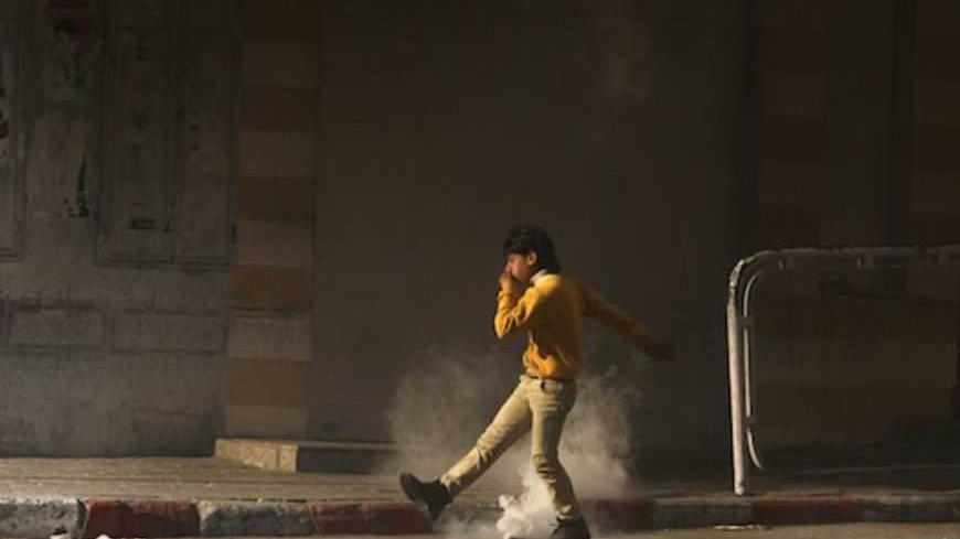 A Palestinian youth tries to kick a tear gas canister back to Israeli troops during clashes with stone-throwers that broke out after a rally in the West Bank city of Hebron to show solidarity with prisoners on hunger strike in Israeli jails February 18, 2013. Palestinians in the West Bank held demonstrations to show solidarity with prisoners on hunger strike in Israeli jails on Monday, some of which sparked clashes with Israeli forces.    REUTERS/Ammar Awad (WEST BANK - Tags: POLITICS CIVIL UNREST TPX IMAGE