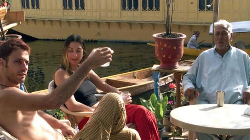 Israeli tourists sit with the owner of a Kashmir houseboat (R) in Srinagar August 19, August 2004. Kashmir, once a tourist haven but now the centre of a bloody Islamic insurgency, seems like a most unlikely destination for Israelis who are themselves battling Palestinian Islamic militants at home. REUTERS/Danish Ismail  FK/SH - RTR8W4T