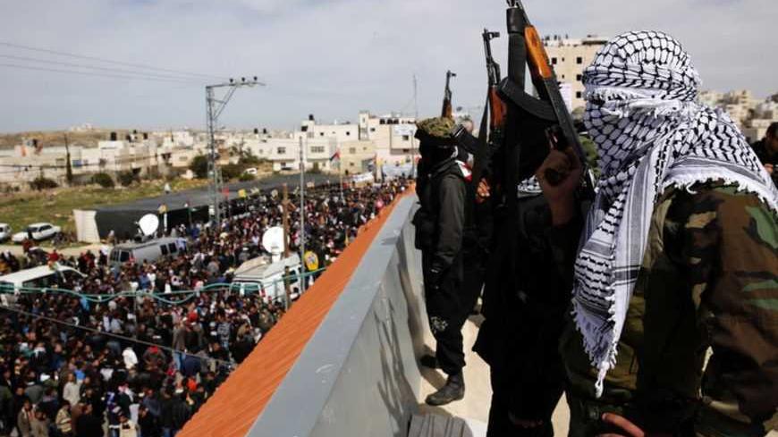 Masked Palestinian gunmen hold weapons atop a roof during the funeral of Arafat Jaradat in the West Bank village of Se'eer, near Hebron February 25, 2013. Jaradat's death in an Israeli jail on Saturday and a hunger strike by four other Palestinian inmates have raised tension in the occupied territory after repeated clashes between stone-throwers and Israeli soldiers in recent days. Israeli troops, on high alert, took up positions outside Jaradat's home village of Se'eer, in likely earshot of the bursts of a