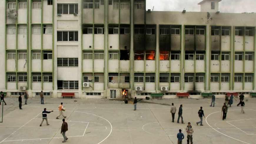 Palestinians look at a burning building at the al-Quds University after it was attacked by gunmen in Gaza February 2, 2007. Fighting between Palestinian factions escalated across Gaza on Friday, killing at least 11 people as Hamas overran compounds used by President Mahmoud Abbas' forces and Fatah set the Islamic University ablaze. REUTERS/Mohammed Salem (GAZA) - RTR1LWWO