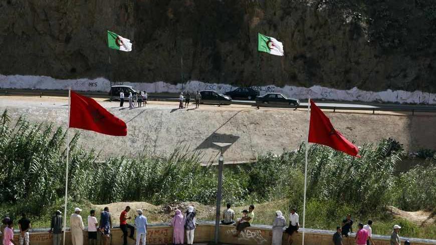 People stand near a border post on the Algerian side of the Morocco-Algeria border in the north east of Morocco July 31, 2011. Morocco's King Mohammed renewed calls on Saturday to normalise ties and reopen borders with wealthier neighbour Algeria, saying that Rabat wants to build an integrated North African economic bloc. Morocco closed the border following a 1994 Islamist militant attack in Marrakesh, which it blamed on Algeria's secret service, and the border region remains tense. REUTERS/Youssef Boudlal 