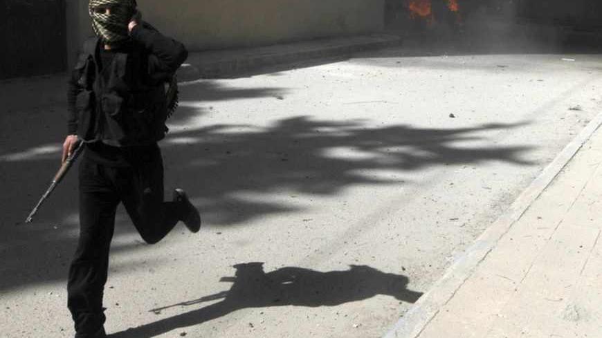 A fighter from Islamist Syrian rebel group Jabhat al-Nusra runs with his weapon as their base is shelled in Raqqa province, eastern Syria, March 14, 2013. REUTERS/Hamid Khatib (SYRIA - Tags: CONFLICT POLITICS) - RTR3EZGW