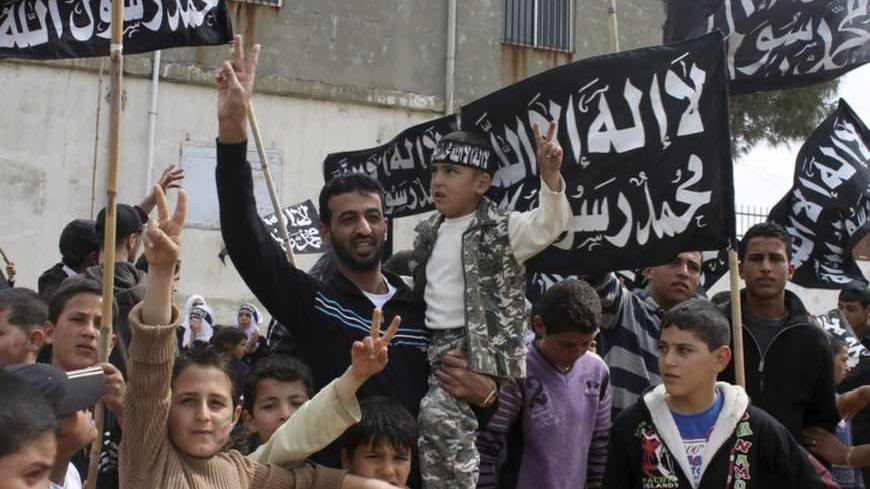 Syrian refugee children and men gesture, as they hold flags and wear headbands during a protest marking two years since the start of the uprising in the Wadi Khaled area, northern Lebanon March 15, 2013. The headbands and flags read  "There is no God but Allah and Mohammad is the messenger of Allah" . REUTERS/Roula Naeimeh (LEBANON - Tags: POLITICS CIVIL UNREST CONFLICT) - RTR3F19U