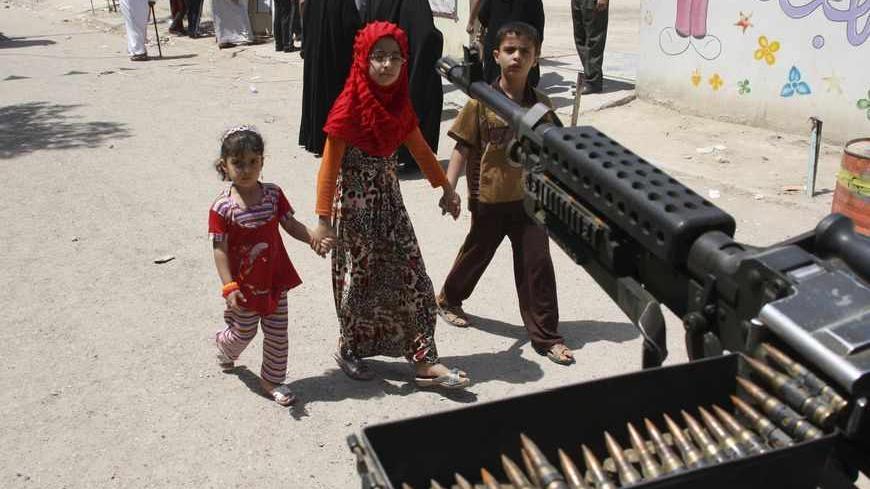 Children walk by a machine-gun near election centre in Baghdad April 20, 2013. Iraqis voted for provincial councils on Saturday in their first ballot since U.S. troops left the country, a key measure of political strength before parliamentary elections next year. Iraqi politics are deeply split along sectarian lines with Prime Minister Nuri al-Maliki's government mired in crisis over how to share power among Shi'ites, Sunni Muslims and ethnic Kurds who run their own autonomous region in the north. Violence 