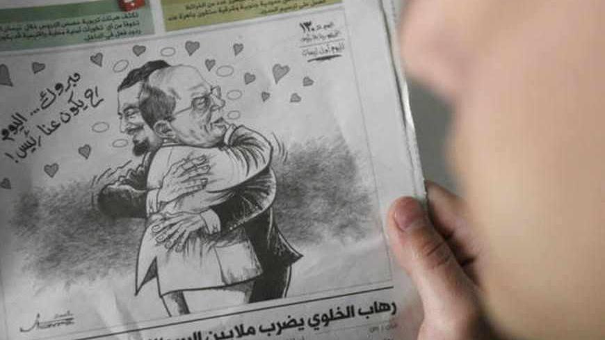 A Lebanese man looks at a caricature in the newspaper al-Balad showing anti-Syrian majority leader Saad Hariri and opposition leader Michel Aoun hugging and congratulating each other for the "election of a Lebanese president", in Beirut on April 01, 2008.  Lebanese newspapers today offered their readers a brief moment of wishful thinking by announcing in an April Fools message that the country's protracted political crisis was over and that a president had been elected.
AFP PHOTO/RAMZI HAIDAR (Photo credit 