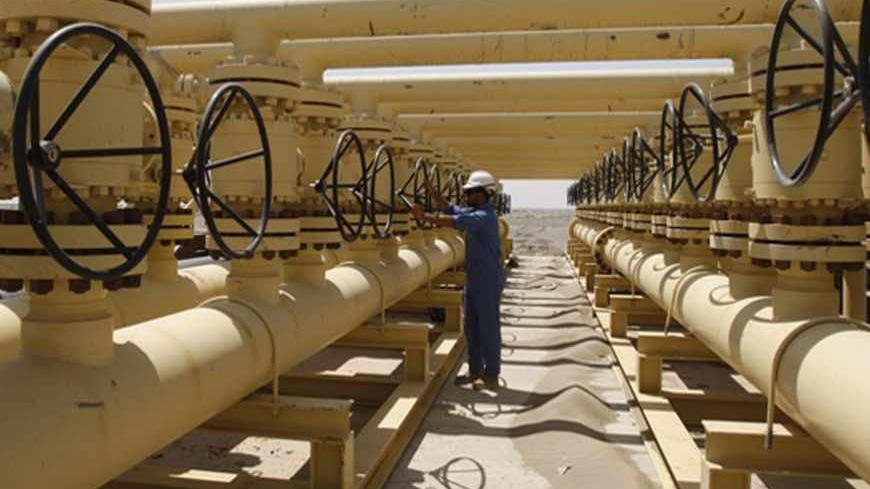 A worker adjusts a pipe at the Nassiriya oilfield in Nassiriya, 300km (185 miles) southeast of Baghdad,September 8, 2012. Production from Iraq's southern oilfields is at 2.5 million barrels per day as the country edges closer to becoming the world's biggest source of new supplies over the next few years, a senior Iraqi oil official said. Picture taken September 8, 2012. REUTERS/Atef Hassan (IRAQ - Tags: ENERGY BUSINESS) - RTR37U0R