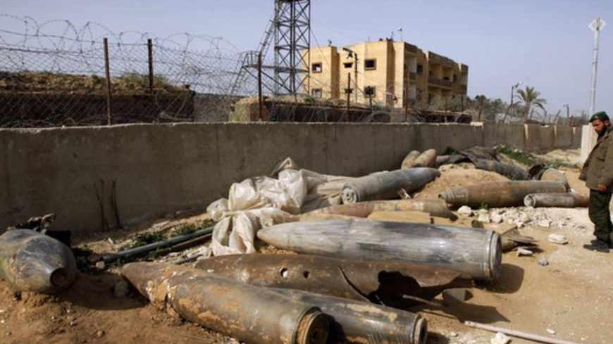 A member of Hamas security forces looks at the remains of spent ammunition and unexploded bombs, fired by Israeli warplanes during Israel's 22-day offensive, in Rafah in the southern Gaza Strip January 26, 2009. Some 1,300 Palestinians, including at least 700 civilians, were killed, Palestinian medical officials said, in the offensive Israel launched in the Hamas-ruled Gaza Strip with the declared aim of ending cross-border rocket attacks. REUTERS/Ibraheem Abu Mustafa (GAZA) - RTR23WJ0